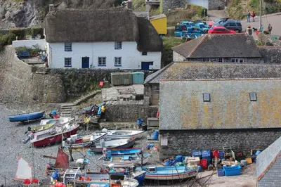 a group of boats sitting on the sand near a building at Old Temperance House in Saint Keverne