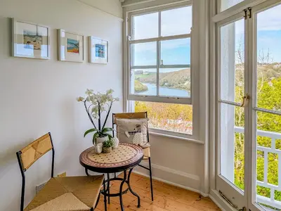 a table and chairs in a room with windows at Denzell in Looe