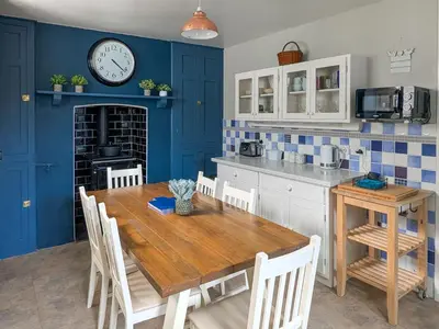 a kitchen with a wooden table and a clock on the wall at Denzell in Looe