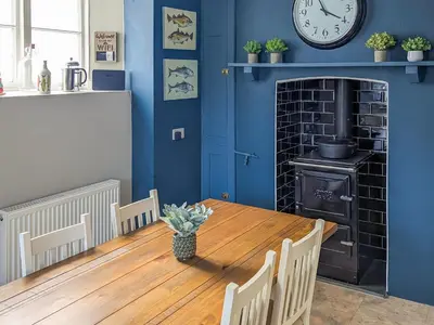 a dining room with a table and a clock on the wall at Denzell in Looe