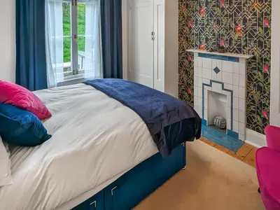 a bedroom with a large bed with a fireplace at Denzell in Looe