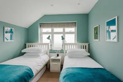 two beds in a room with blue walls at 4 The Sands in Polzeath