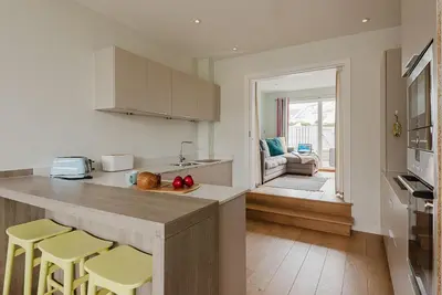 a kitchen with a counter and two yellow stools at 4 The Sands in Polzeath