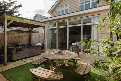 a patio with a table and benches and a grill at 4 The Sands in Polzeath