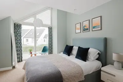 a bedroom with a bed and a large window at 4 The Sands in Polzeath