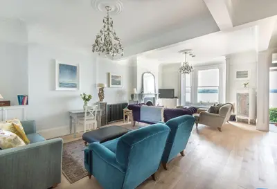 a living room with blue chairs and a chandelier at 5 The Terrace in Padstow