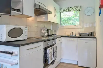 a kitchen with white cabinets and a microwave at Finest Retreats - Lanteglos Villa in Camelford