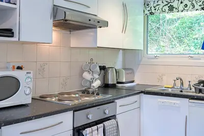 a kitchen with white cabinets and a sink and a microwave at Finest Retreats - Lanteglos Villa in Camelford