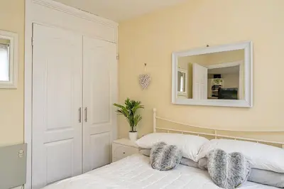 a bedroom with a white bed and a mirror at Finest Retreats - Lanteglos Villa in Camelford