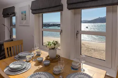 a dining room table with a view of the beach at Harts Loft - On Beach - Panoramic Sea Views - By Harbour in St Ives