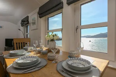 a dining room table with plates and glasses and a window at Harts Loft - On Beach - Panoramic Sea Views - By Harbour in St Ives