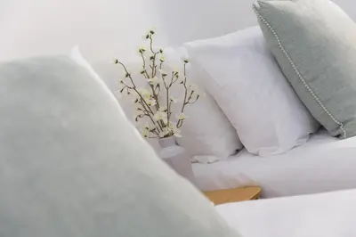a white couch with white pillows and a vase with flowers at Harts Loft - On Beach - Panoramic Sea Views - By Harbour in St Ives