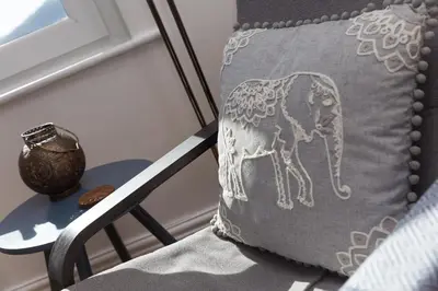 a pillow sitting on a chair next to a table at Harts Loft - On Beach - Panoramic Sea Views - By Harbour in St Ives