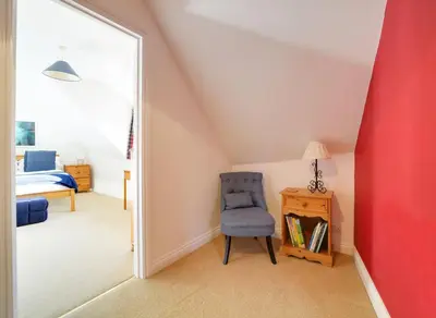 a bedroom with a blue chair and a mirror at Casa Piedra in Polzeath