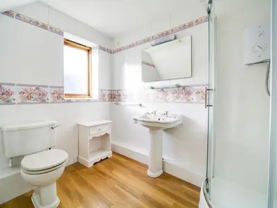 a white bathroom with a toilet and a sink at Casa Piedra in Polzeath
