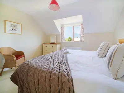 a bedroom with a white bed and a window at Chy Petroc in Polzeath