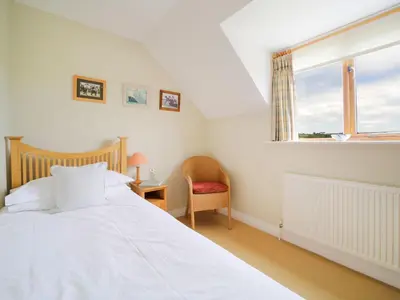 a bedroom with a bed and a chair and a window at Chy Petroc in Polzeath
