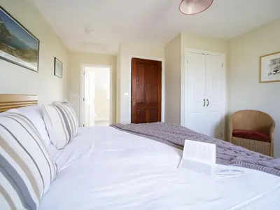 a bedroom with a large white bed and a chair at Chy Petroc in Polzeath