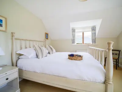 a bedroom with a white bed with a basket on it at Chy Petroc in Polzeath