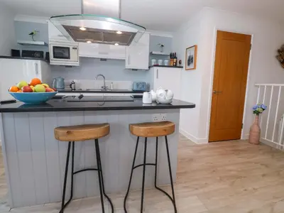 a kitchen with two bar stools and a bowl of fruit at Sea Breeze in Carbis Bay