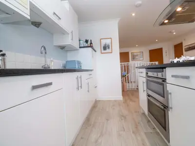 a kitchen with white cabinets and black counter tops at Sea Breeze in Carbis Bay