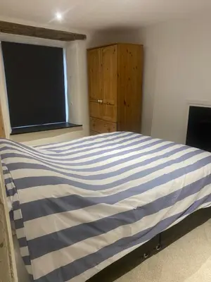 a bedroom with a blue and white striped bed at Hideaway Cottage in Camelford