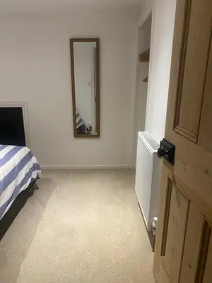 a bedroom with a bed and a mirror on the wall at Hideaway Cottage in Camelford
