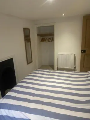 a bedroom with a blue and white striped bed at Hideaway Cottage in Camelford