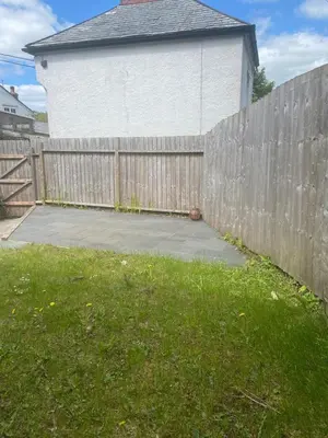 a wooden fence next to a yard with a driveway at Hideaway Cottage in Camelford