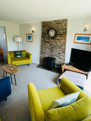 a living room with a yellow couch and a clock on a brick wall at Moogara in Gorran Haven