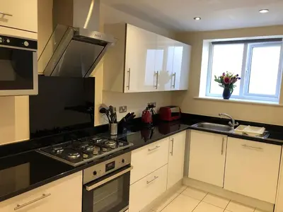 a kitchen with white cabinets and a stove top oven at Retallack hot tub lodge - 4 ensuites - luxury stay in Saint Columb Major