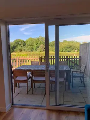 a sliding glass door leading to a patio with a table and chairs at Retallack hot tub lodge - 4 ensuites - luxury stay in Saint Columb Major