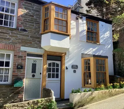 a white house with wooden windows and a door at Charming Fishing Cottage in Polruan