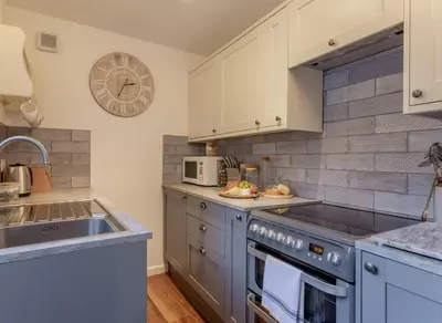 a kitchen with blue cabinets and a sink at Charming Fishing Cottage in Polruan