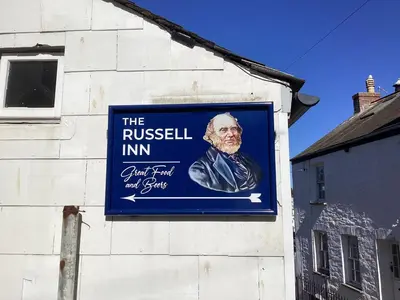 a sign for the russian inn on the side of a building at Charming Fishing Cottage in Polruan