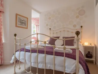a bedroom with a white bed with purple sheets at Charming Fishing Cottage in Polruan