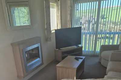 a living room with a fireplace and a television at Sea Breeze Villa near to Newquay sleeping 6 guests in Newquay