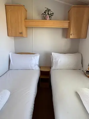 two beds in a small room with white pillows at Family-Friendly 3-Bed Caravan Recently Renovated on Seven Bays Holiday Park, Padstow in St Merryn
