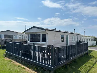 a white tiny house with a black fence at Family-Friendly 3-Bed Caravan Recently Renovated on Seven Bays Holiday Park, Padstow in St Merryn