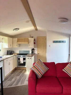 a living room with a red couch in a kitchen at Family-Friendly 3-Bed Caravan Recently Renovated on Seven Bays Holiday Park, Padstow in St Merryn