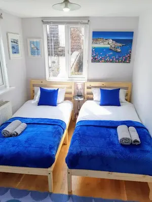 two beds in a room with two windows at Chapel Street Retreat in St Ives