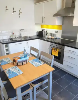 a kitchen with a table with chairs and a sink at Chapel Street Retreat in St Ives