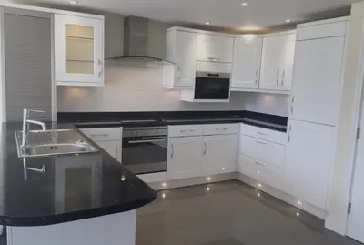 a kitchen with white cabinets and a black counter top at Foxwood in Kenwyn