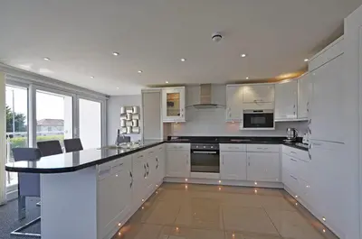 a kitchen with white cabinets and a black counter top at Foxwood in Kenwyn