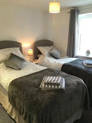 a bedroom with two beds and a window at Pencarrick in Kenwyn