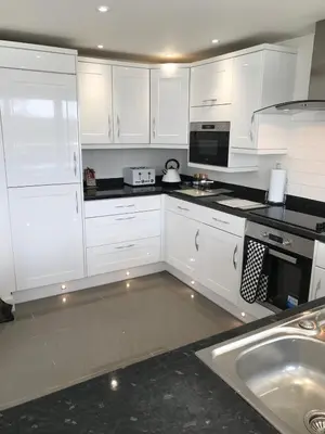 a white kitchen with white cabinets and a sink at Pencarrick in Kenwyn