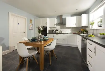 a kitchen with a wooden table and white cabinets at Puffin Way in Hayle