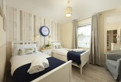a bedroom with two beds and a clock on the wall at Puffin Way in Hayle