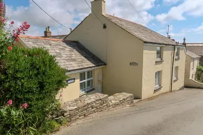 a cottage in a village with a stone wall at Hilldene in Tintagel