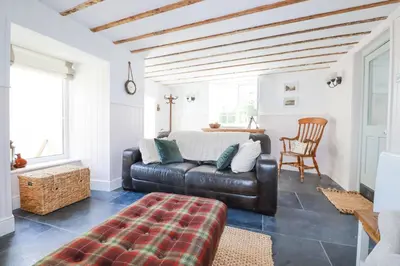 a living room with a leather couch and a bed at Hilldene in Tintagel